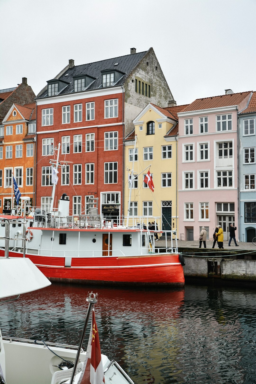 Colourful harbour houses in Copenhagen at dusk with people walking along the quay